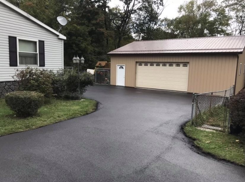 Curved asphalt driveway leading up to a detached garage
